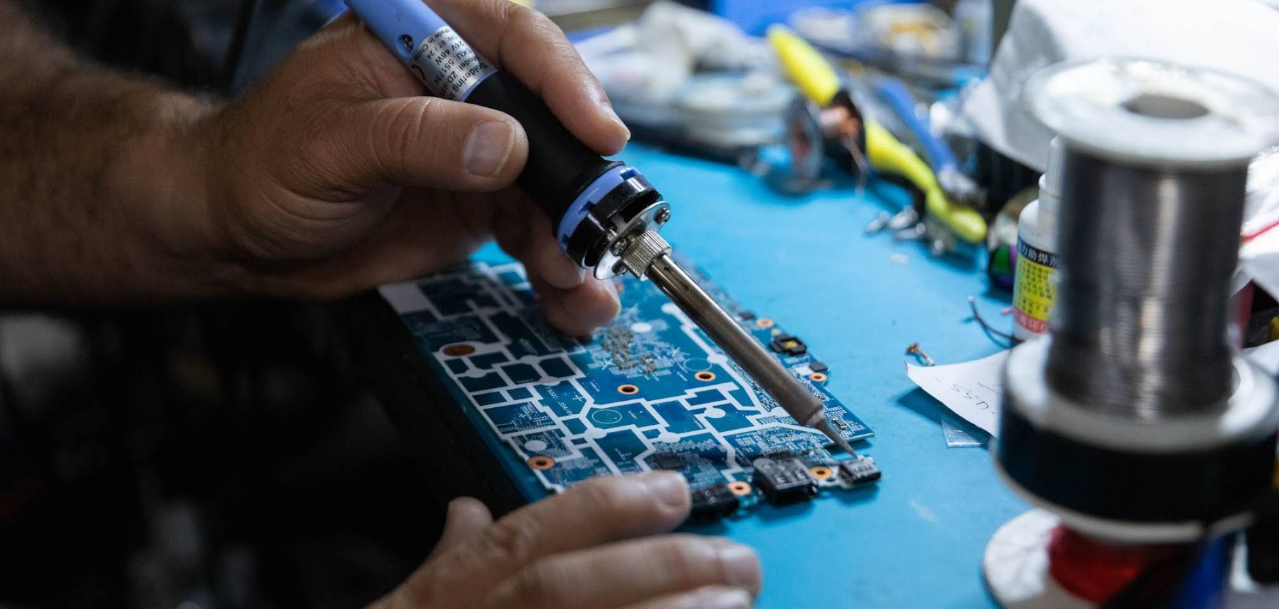 Technician repairing a smartphone motherboard with precision tools